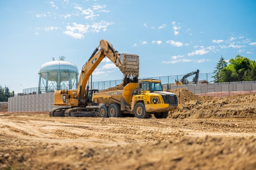 F200 excavator loading haul truck in front of water tower