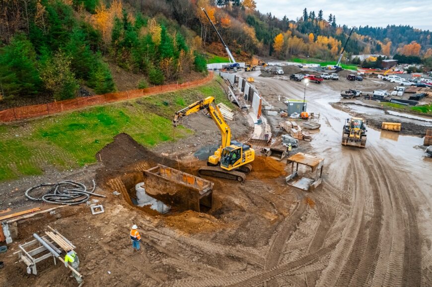 Algona excavator lowering trench box for pipe crew