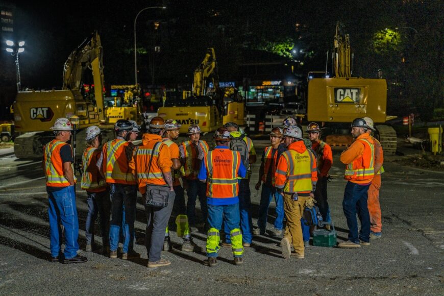 B2R large group of construction employees having a safety meeting at night before construction starts