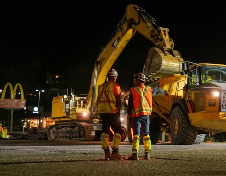 Two employees monitoring an excavator loading a haul truck